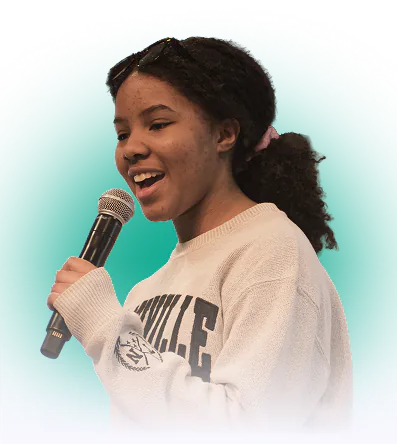 Young woman singing into a microphone while wearing a white sweatshirt.